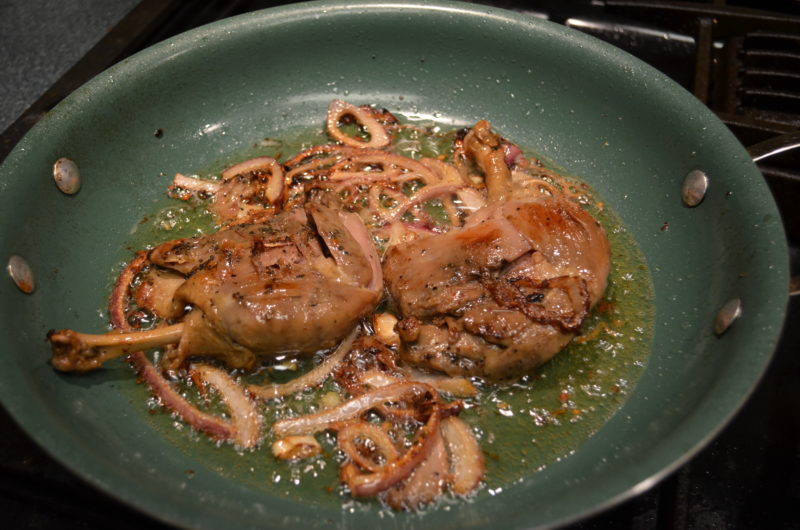 confit duck legs in pan with butter